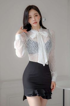 Woman in a white lace blouse and black skirt with a black bra visible underneath
