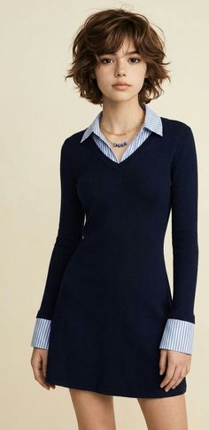 Woman with short brown hair wearing a navy dress over a striped shirt