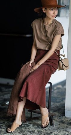 Woman in a brown hat and midi skirt sitting indoors