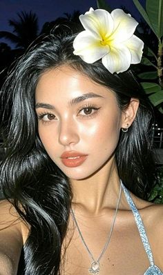 Woman with a white flower in her hair wearing a bikini top at night
