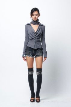 Woman in a gray top, denim shorts, and thigh-high socks on a white background