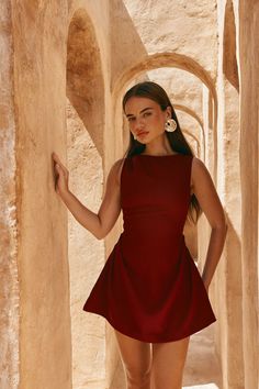 Woman in a red dress posing in an arched outdoor corridor