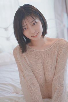 Woman with short hair wearing a light knitted sweater indoors