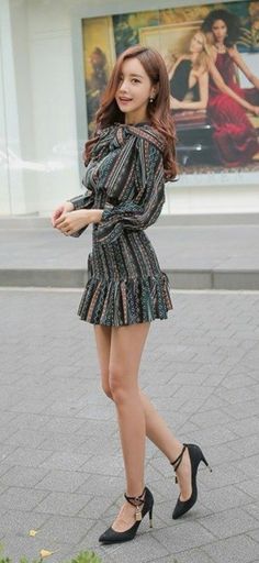 Woman in a patterned dress and high heels standing outdoors