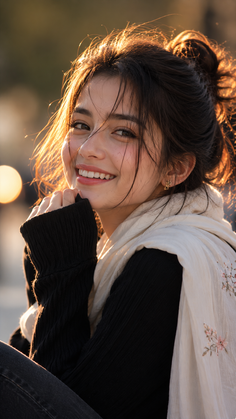 Young woman with a messy bun and embroidered scarf smiling at golden hour