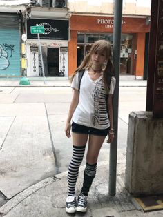 Young woman with pigtails and striped socks standing on a city street