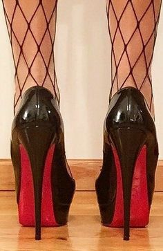 Legs in fishnet stockings and black high heels with red soles