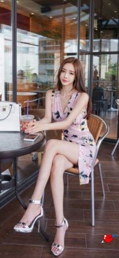Woman in a floral dress and high heels sitting at a cafe table