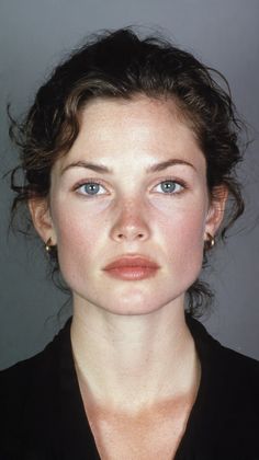 Woman with blue eyes and dark curly hair wearing gold hoop earrings