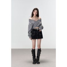 Woman in an off-shoulder top, mini skirt, and knee-high boots standing indoors