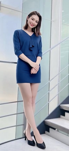 Woman in a blue dress and black high heels smiling indoors