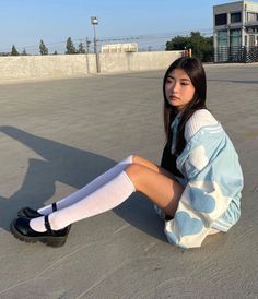 Young woman in a blue varsity jacket and white knee socks sitting outdoors
