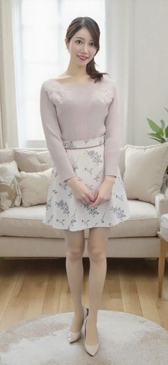 Woman in a light pink top and floral skirt standing indoors