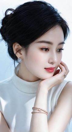 Woman with black hair in an updo wearing a white turtleneck and jewelry