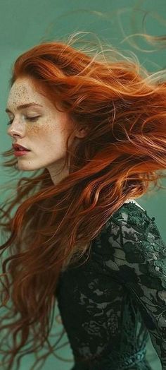 Woman with red hair and freckles in a lace dress against a teal background