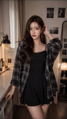 Woman in a black dress and plaid shirt posing indoors