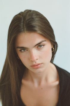 Woman with long brown hair and green eyes wearing gold hoop earrings