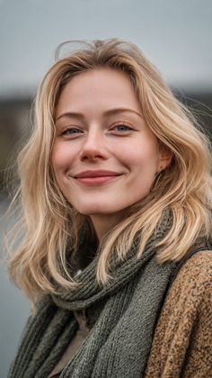 Blonde woman with a green scarf and knitted sweater, smiling at the camera