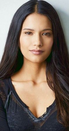 Woman with long dark hair wearing a black v-neck top