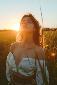 Woman with closed eyes and head tilted back in a field at golden hour