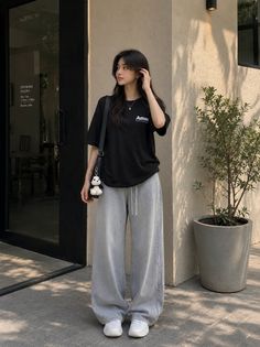 Woman in a black t-shirt and wide leg pants standing outdoors