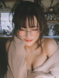 Woman with messy bun and glasses wearing an off-shoulder sweater indoors