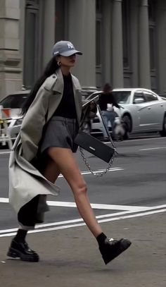 Woman in a trench coat and shorts walking on a city street