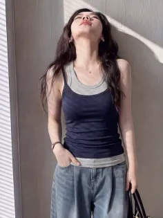 Woman in layered tank tops and wide leg jeans with dramatic lighting