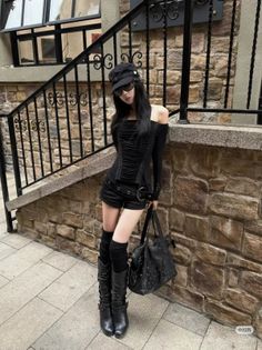 Woman in a black gothic outfit with long hair and sunglasses posing outdoors