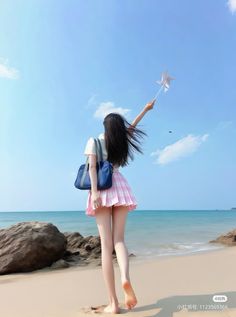 Woman with long hair holding a pinwheel on a beach with a blue sky