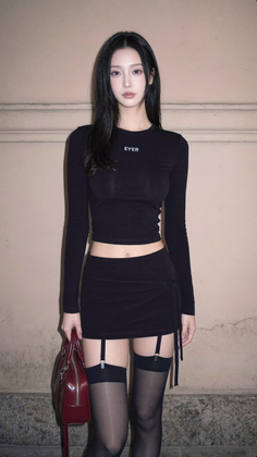 Woman in a black crop top and mini skirt with stockings and garter straps