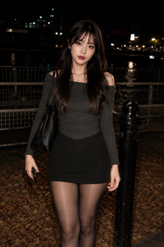 Woman in an off-shoulder top and mini skirt standing outdoors at night