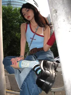 Woman in a blue tank top and denim skirt with platform shoes outdoors