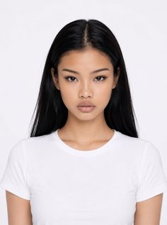 Woman with long black hair wearing a white t-shirt in a studio portrait