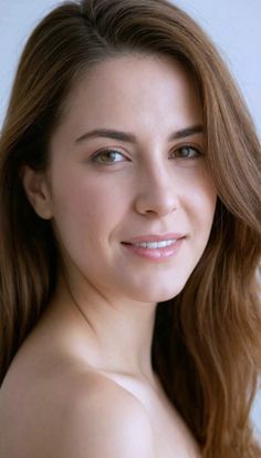 Woman with long brown hair and bare shoulders smiling at the camera