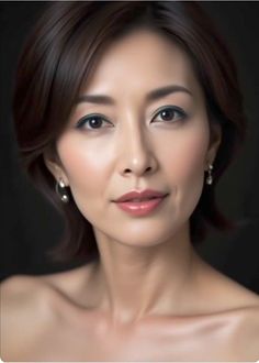 Woman with short brown hair and earrings, exposed shoulders against a dark background