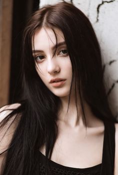Woman with long dark hair wearing a black top, looking directly at the viewer