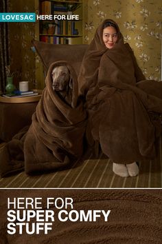 Woman and dog wrapped in brown blankets in a cozy indoor setting