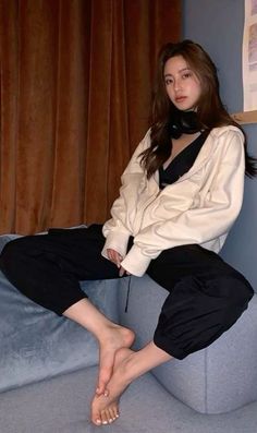 Woman with long hair wearing a hoodie and black pants, sitting on a couch