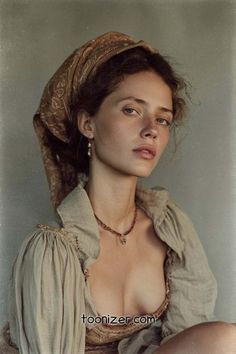 Woman with a headscarf and freckles, wearing a loose shirt with exposed cleavage