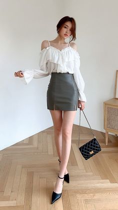 Woman in an off-shoulder top and mini skirt holding a quilted handbag
