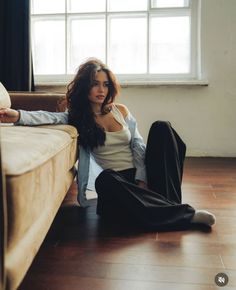Woman with long hair sitting on the floor next to a couch