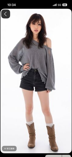 Woman with long hair wearing a gray sweater, denim shorts, and cowboy boots