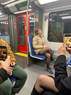 Woman in a puffer jacket and tights posing for a photo in a subway car