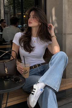 Woman with long brown hair sitting at an outdoor cafe with an iced coffee