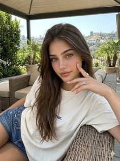 Woman with long brown hair wearing a t-shirt and denim shorts outdoors