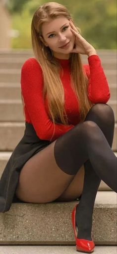 Woman with long hair in a red top and black skirt sitting outdoors