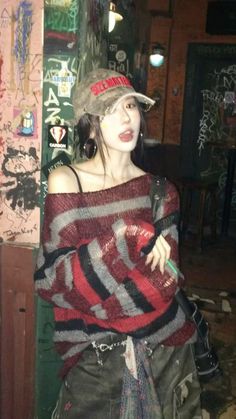 Woman in a striped sweater and camouflage hat against a graffiti-covered wall