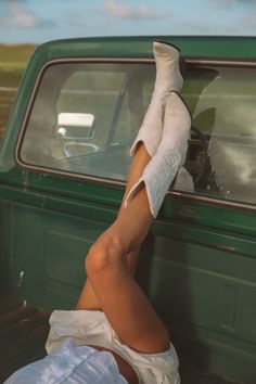 Person with legs in white cowboy boots propped on a green truck