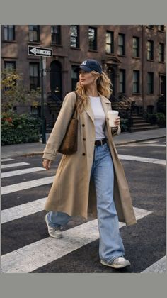 Woman in a trench coat and wide leg jeans crossing a street